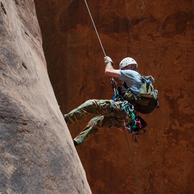 Climber rappelling down cliff